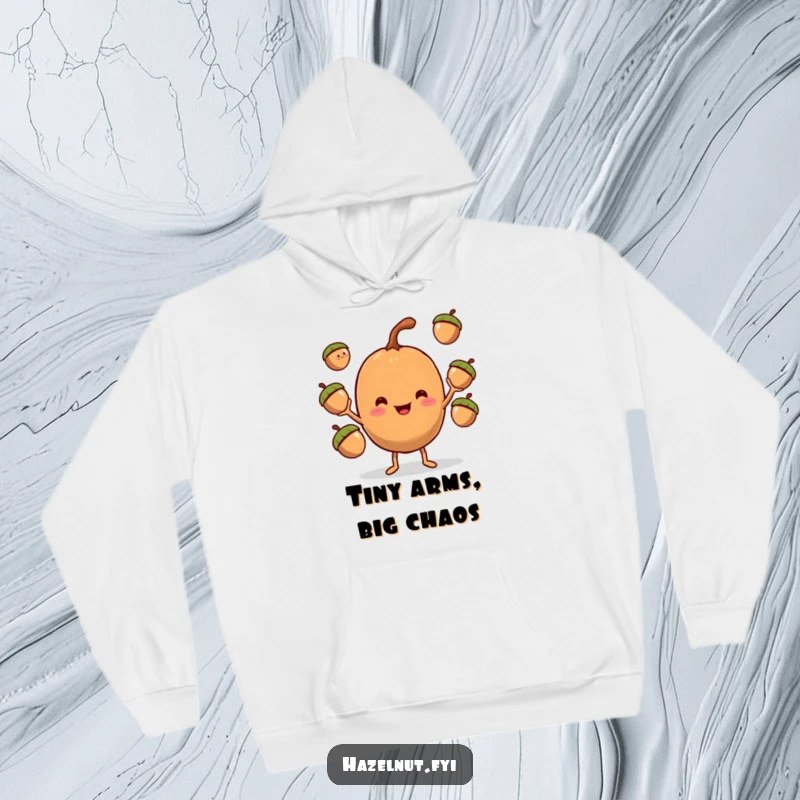 Funny Hazelnut Juggler Hoodie, a smiling hazelnut with tiny arms masterfully juggling three acorns, perfect for warmth.